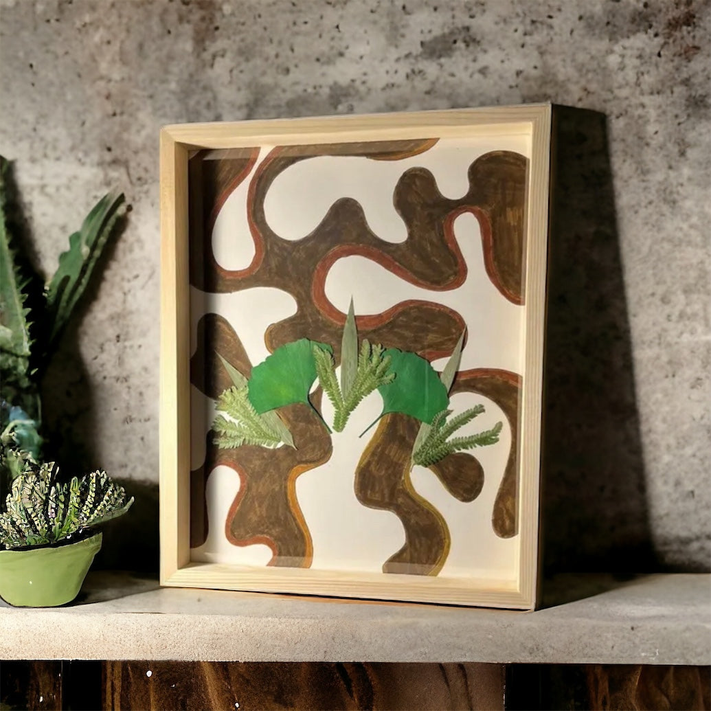 Brown abstract flower art sitting on shelf with plant